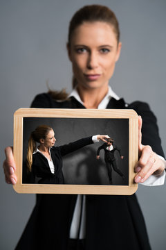 businesswoman showing chalkboard depicting herself as a powerful boss with a male colleague