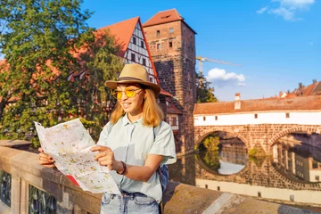 Glückliche asiatische Reisende mit Karte an der Pegnitz in der Nürnberger Altstadt. Reiseorte und Touristenattraktionskonzept © EdNurg