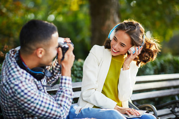 Young man photographing young woman with headphones for social network