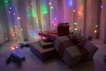 stack of christmas presents on a wooden table with colorful lights in the background