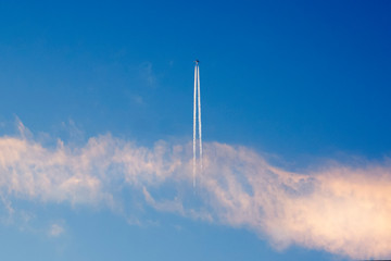 The plane flies up leaving a trail in the blue sky