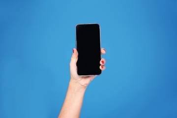 Hand with mobile phone on blue background.