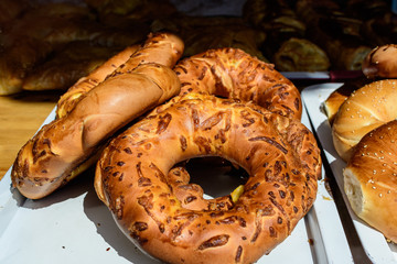 Fresh crispy bagels with white cheese, in direct sun light, displayed for sale at a bakery at a...