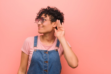 Young mixed african american teenager woman trying to listening a gossip.