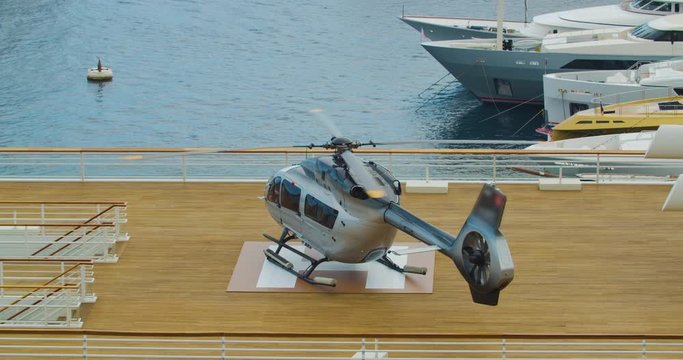 Modern helicopter standing at the take-off station and preparing for flight, propeller in motion.