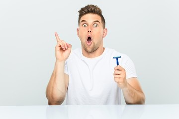 Young man holding a razor blade having some great idea, concept of creativity.