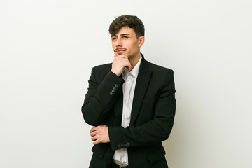 Young business hispanic man looking sideways with doubtful and skeptical expression.