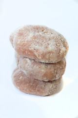 Three frozen meat cutlets stacked on top of each other on a white background