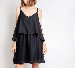 Young woman wearing simple mini black dress isolated on light grey background. Copy space
