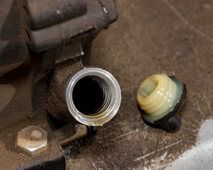 Closeup of small gas engine on lawn mower with oil fill plug removed showing oil level inside of...