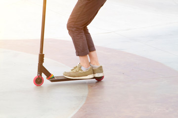 young man on kisck scooter trains to ride fast and perform tricks in skate park