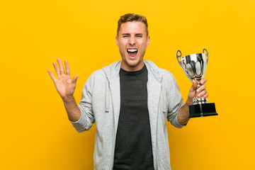 Young caucasian man holding a trophy celebrating a victory or success