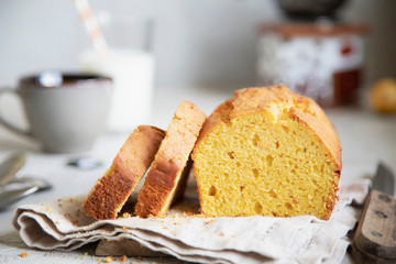Pumpkin cake on beige dish cloth with cup of tea, glass of milk and tree branch on background. Autumn dessert.