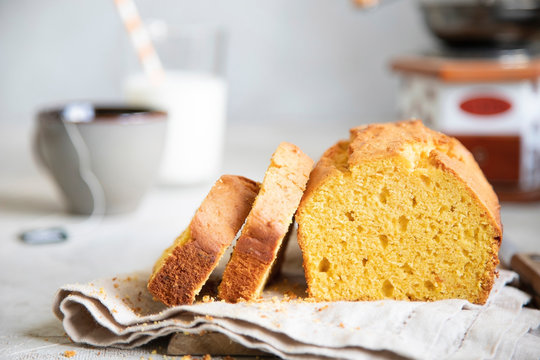 Pumpkin cake on beige dish cloth with cup of tea, glass of milk and tree branch on background. Autumn dessert.
