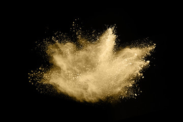 Golden powder explosion on black background. Freeze motion.