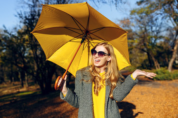 Girl, with yellow umbrella, in the Park with yellow leaves, autumn time