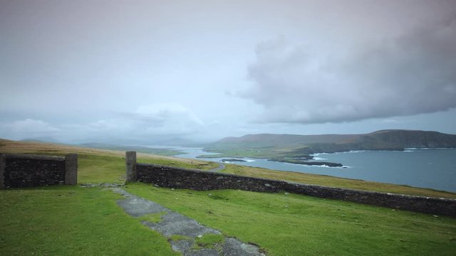 footage of bray head on the ring of kerry in the south coast of ireland on a stormy day showing battering waves and green grass on rocky coastline