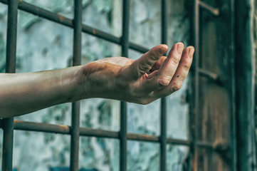 The prisoner's hands stick out of the bars. Request for help. Hunger.