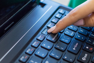 finger pushing delete button on a keyboard of computer