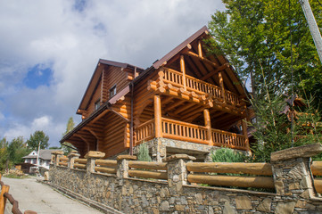 Jaremche/Ukraina - October 16 2019: A beautiful stone fence made of boulders with a wooden yellow house made of timber.