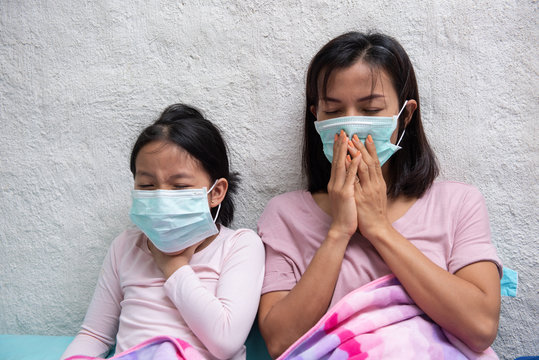 Asian young mother and children daughter wearing protective mask, maybe coughing until sore throat, difficulty swallow, cold, flu or fever go to the hospital meet a doctor