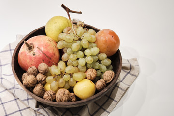 Autumnal fruits in a wooden bowl over a white background