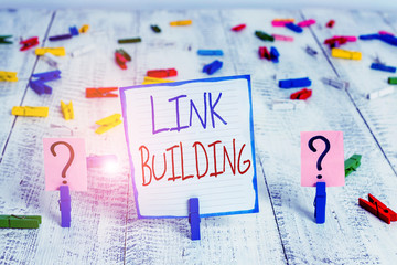 Conceptual hand writing showing Link Building. Concept meaning SEO Term Exchange Links Acquire Hyperlinks Indexed Crumbling sheet with paper clips placed on the wooden table