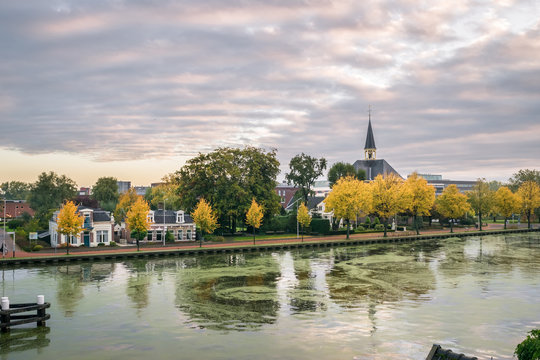 River Rhine in Alphen aan den Rijn, Netherlands with historic church and trees in autumn foliage