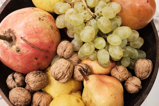 Autumnal fruits in a wooden bowl over a white background