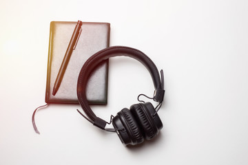 Pen on a notepad with a headphone on