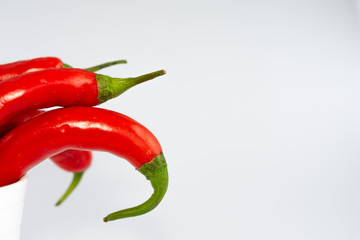 Horizontal macro close-up of red chillies in white bowl on white background with copy space