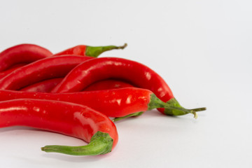 Horizontal close-up of red chillies, some out of focus, on white background with copy space