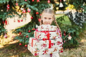 Family Christmas in July. Portrait of girl near christmas tree with gifts. Baby decorating pine. Winter holidays and people concept. Merry Christmas and Happy Holidays Greeting card. Christmas child