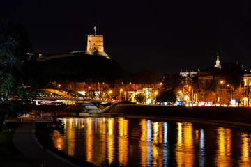 Fototapeta na wymiar Reflections on Neris river with Gediminas Tower in Vilnius Lithuania and Mindaugas Bridge at night in the foreground