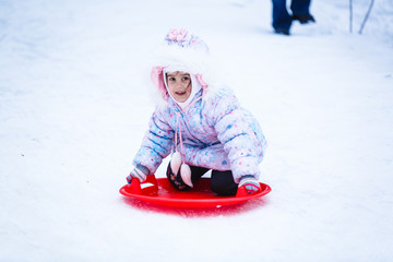 Cute litter girl sliding down on the snow mountain