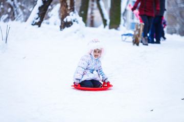 Fototapeta na wymiar Cute litter girl sliding down on the snow mountain