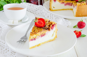 Baked creamy cheesecake with strawberries and crispy shtrezel on a plate on a white wooden...