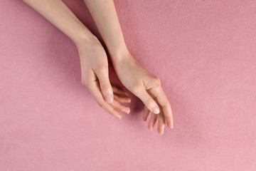Woman with beautiful hands on pink fabric, top view