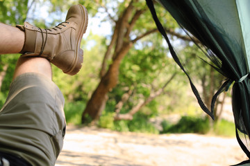 Young man resting in camping tent at forest, view from inside