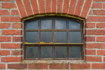 Verrostetes Sprossenfenster an einer Backsteinfassade