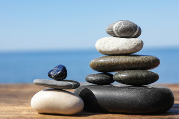 Stacks of stones on wooden pier near sea, space for text. Zen concept