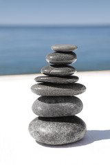Fototapeta na wymiar Stack of stones on wooden pier near sea. Zen concept