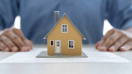 House model with agent asking costumer for contract to buy, get insurance or loan real estate or property.