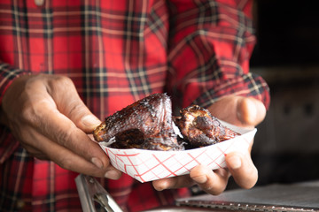 Close up two hands holding Louisiana chicken wings in tray