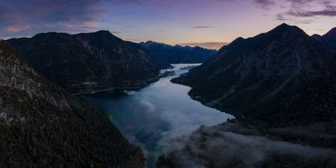 lake plansee at dawn morning with ground fog at fall autumn in tirol
