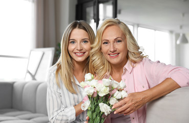 Young woman congratulating her mother in living room