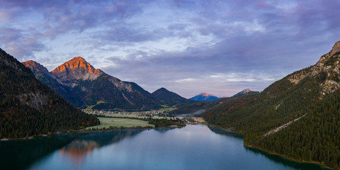 Fototapeta na wymiar red thaneller mountain peak at dawn and reflection in heiterwanger see at fall