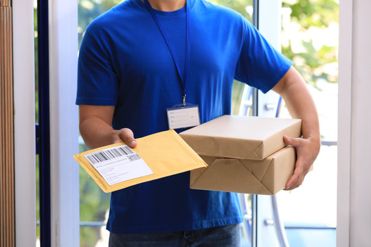 Young courier delivering parcels on doorstep, closeup