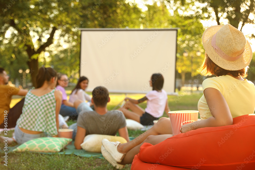 Wall mural Young people with popcorn watching movie in open air cinema. Space for text