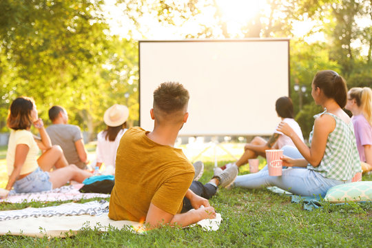 Young People Watching Movie In Open Air Cinema. Space For Text